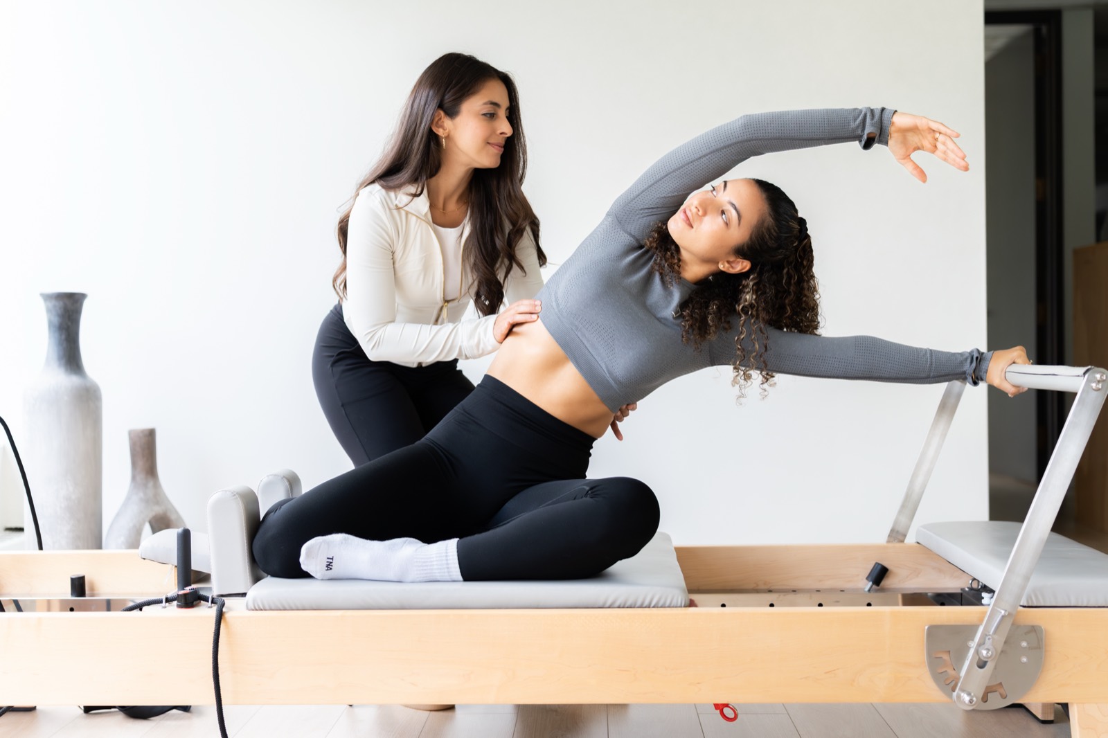 A physiotherapist supporting a client through a side stretch on the reformer